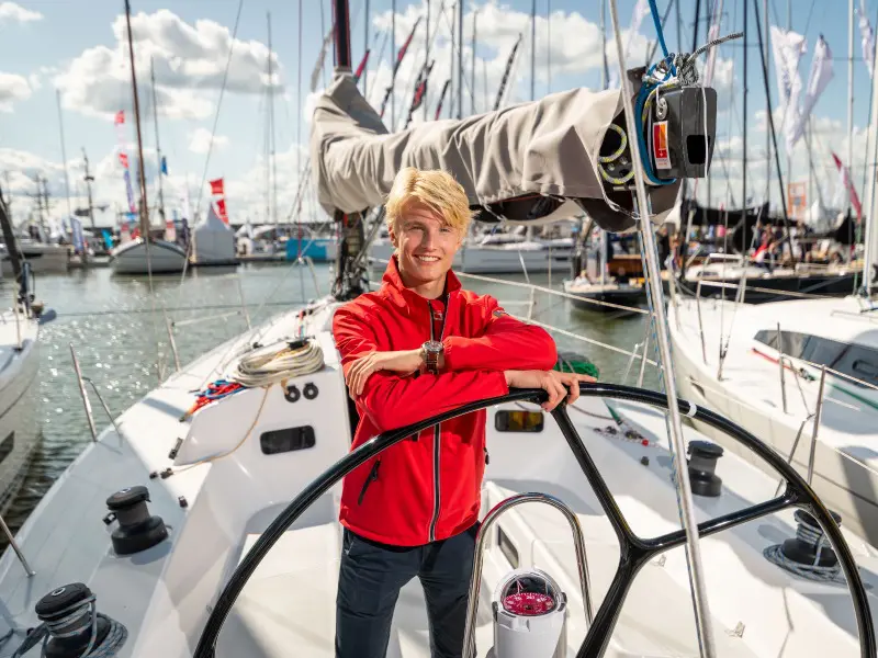 student watersport opleiding op zeilboot met rood jack